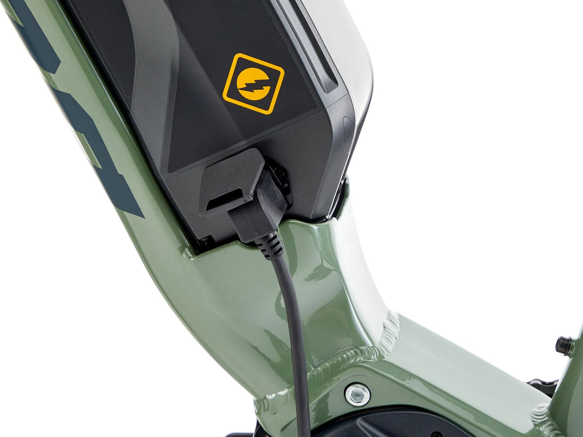 Close-up of a green electric bike with charging cable and visible brand logo.